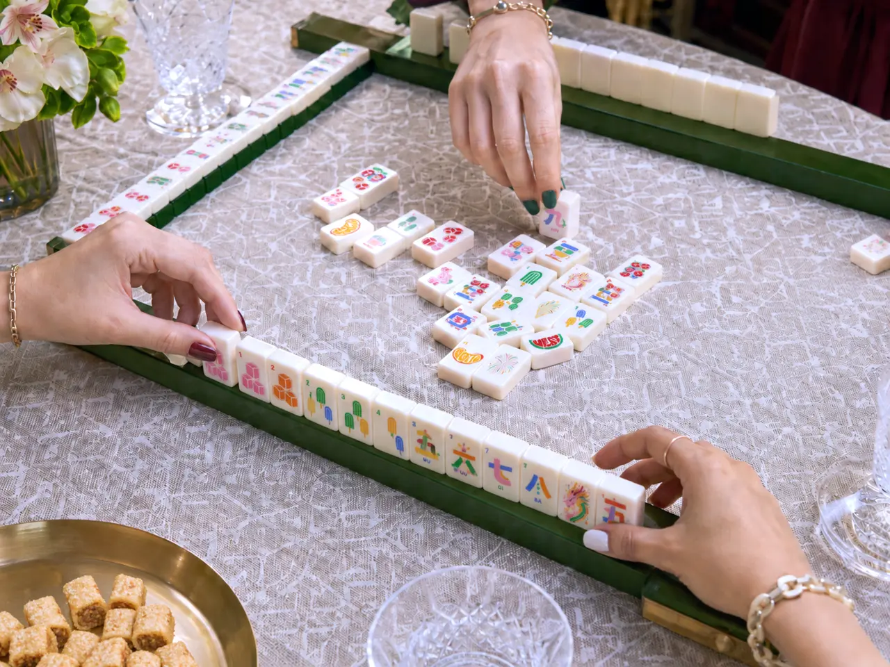 Women with colorful manicures enjoying American Mahjong in an elegant setting
