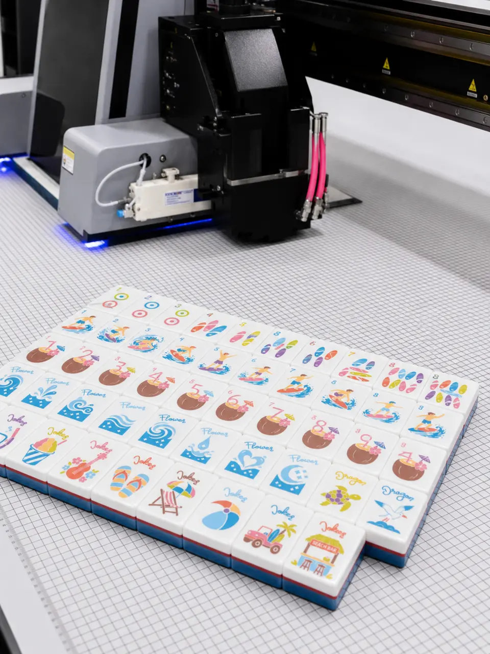 American Mahjong tiles arranged beside precision production equipment
